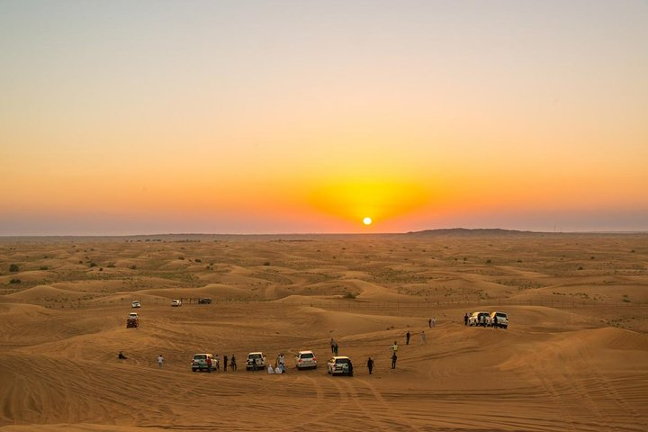 Experience the golden hues of sunset over endless sand dunes while cruising in a 4x4 immersing yourself in the serene beauty of Dubai's desert landscape.
